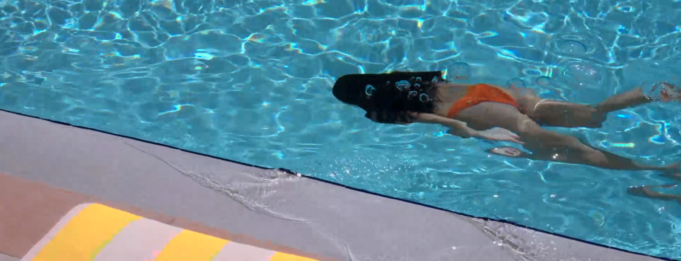 Woman swimming under the water in a pool
